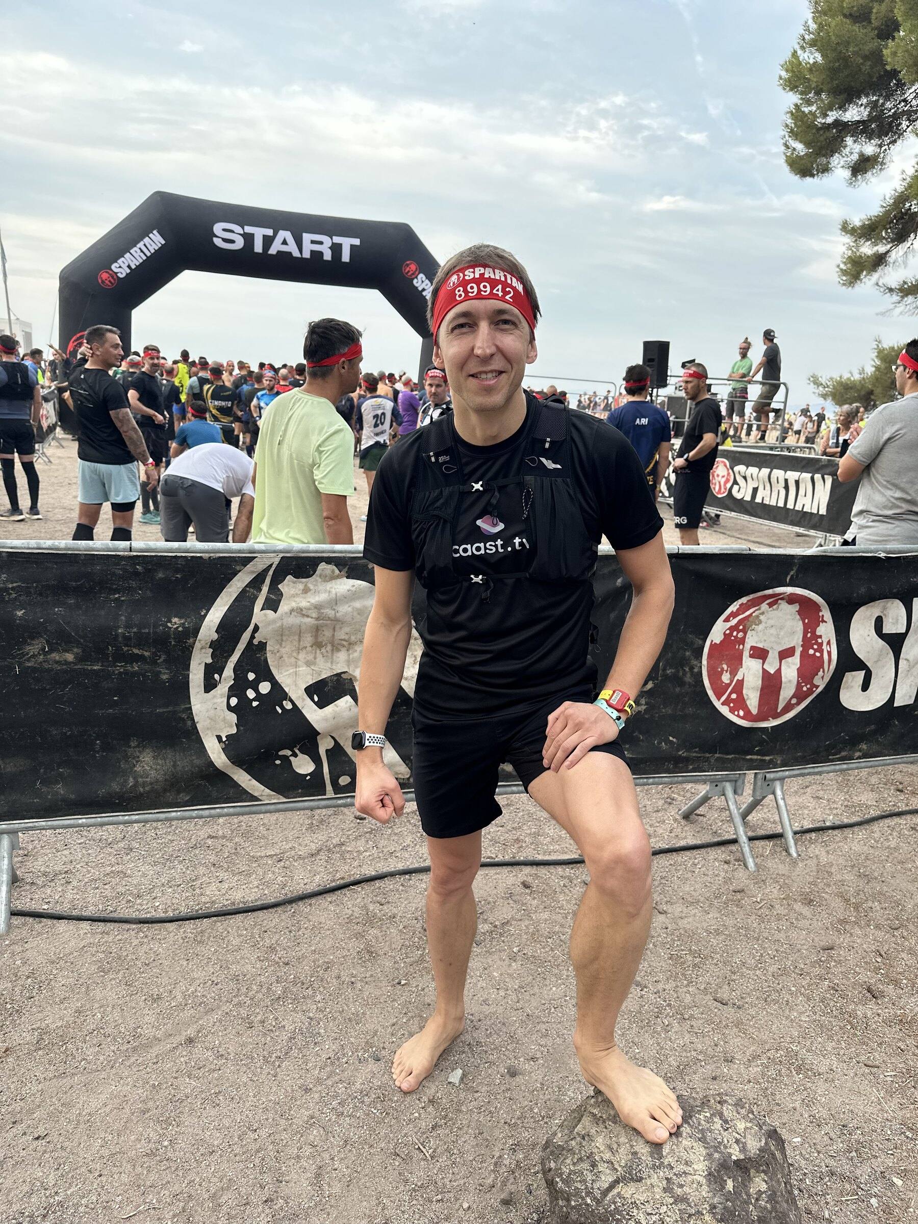 Antoine pieds nus sur un rocher devant l’arche de départ de la Spartan Race, bandeau rouge sur la tête