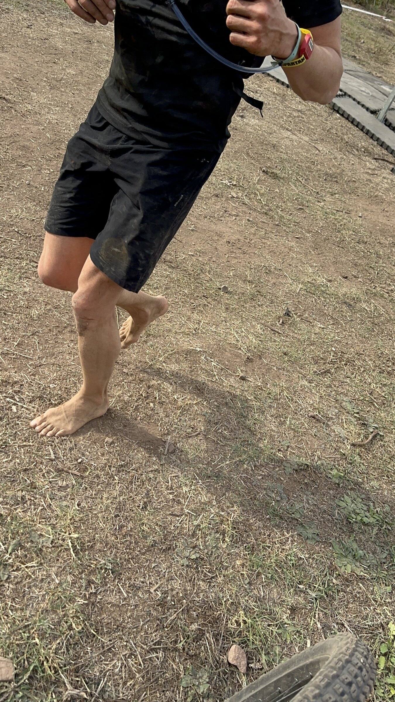 Gros plan sur les pieds nus d’Antoine qui courent sur de l’herbe sèche