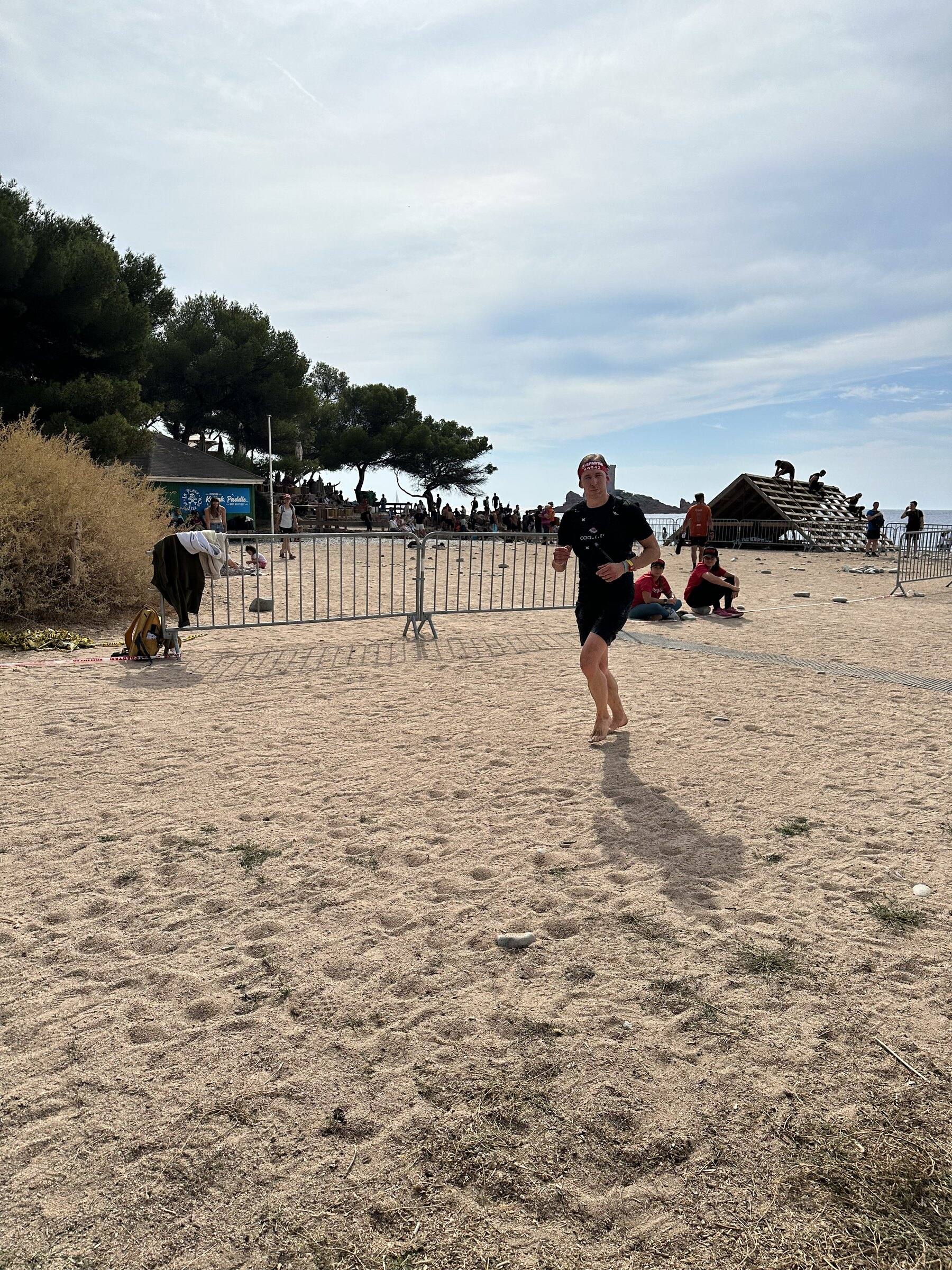 Antoine court pieds nus sur le sable de la plage, entre les barrières