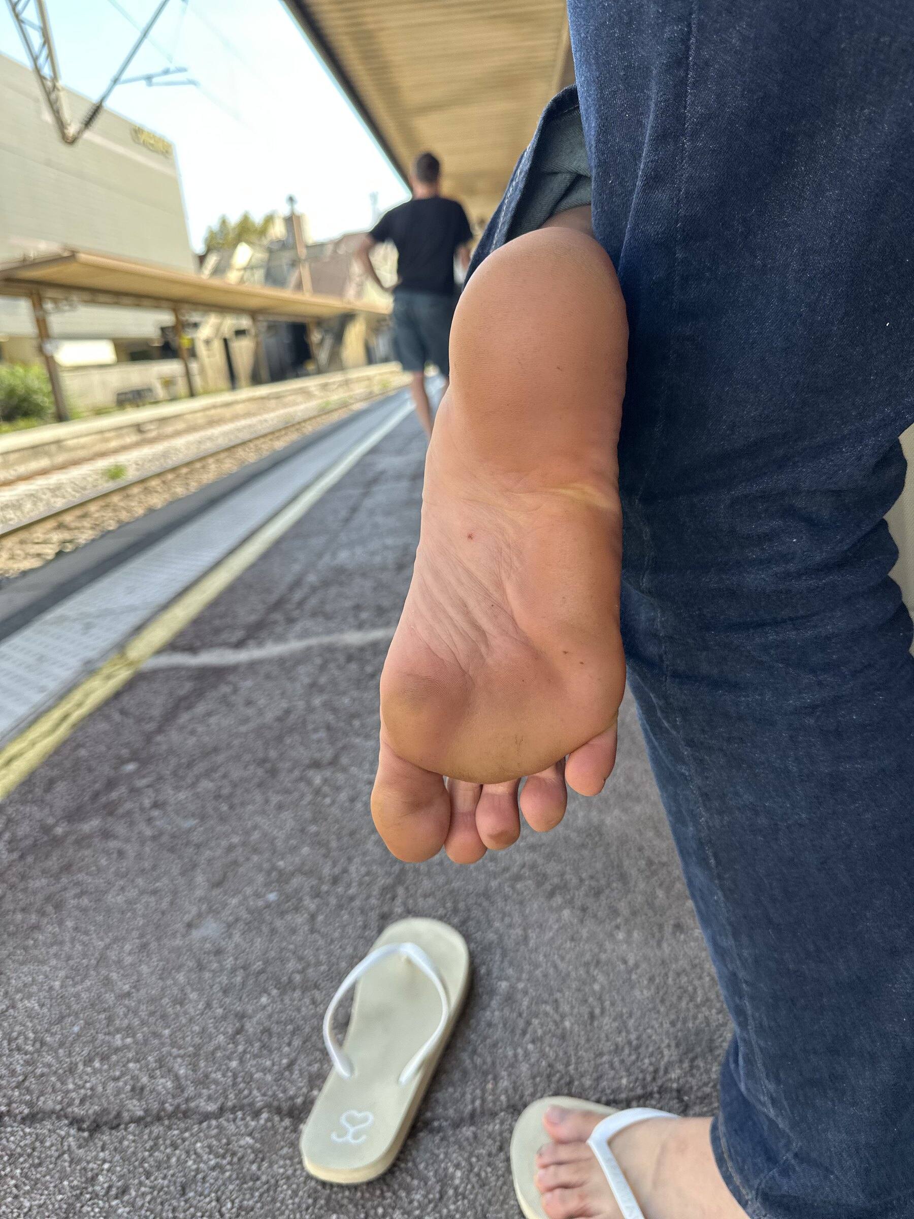 Plante de pied nue, plus foncée mais sans plaie, photographiée sur un quai de gare